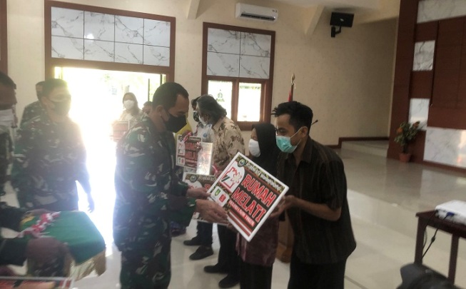 Danrem 074 Warastratama, Kolonel (Inf) Deddy Suryadi (kiri) menyerahkan secara simbolis kepada warga sasaran renovasi rumah tidak layak huni di Makodim 0735 Solo, Selasa (27/7/2021) pagi. (Solopos.com/Ichsan Kholif Rahman)