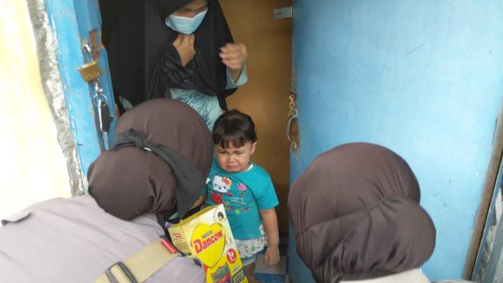 Iptu Uki memberi susu pada putri Ari Prasetyo yang hendak menukar sepatu bekas dengan sekotak susu di Mutihan, Laweyan, Solo, Sabtu (31/7/2021). (Istimewa/Dok Humas Polresta Solo)