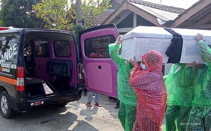 Para warga mengenakan jas hujan saat memanggul peti jenazah warga yang meninggal untuk dibawa ke permakaman umum wilayah Desa Jirapan, Masaran, Sragen, Sabtu (31/7/2021). (Istimewa/Pemdes Jirapan)
