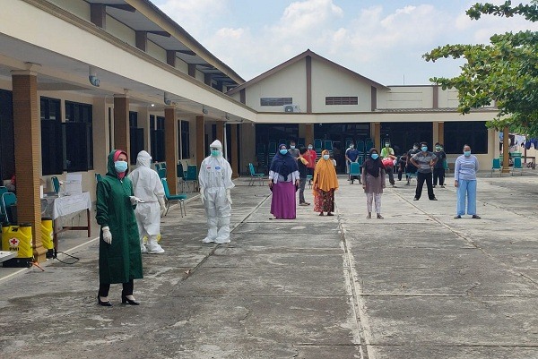 Warga yang menjalani isolasi terpusat di Gedung PGRI Wonogiri berjemur di halaman, Kamis (5/8/2021). (Solopos.com/Rudi Hartono)