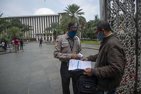 Petugas keamanan mengecek suhu badan dan kartu vaksin warga yang akan menunaikan shalat Jumat di Masjid Istiqlal, Jakarta, Jumat (20/8/2021). Pengurus Masjid Istiqlal kembali membuka pelaksanaan ibadah shalat Jumat setelah ditutup selama masa PPKM Darurat hingga masa perpanjangan saat ini dengan ketentuan jumlah jamaah dibatasi sebanyak 25 persen dari kapasitas masjid dan jamaah wajib menunjukkan kartu vaksin. ANTARA FOTO/Aditya Pradana Putra/rwa.