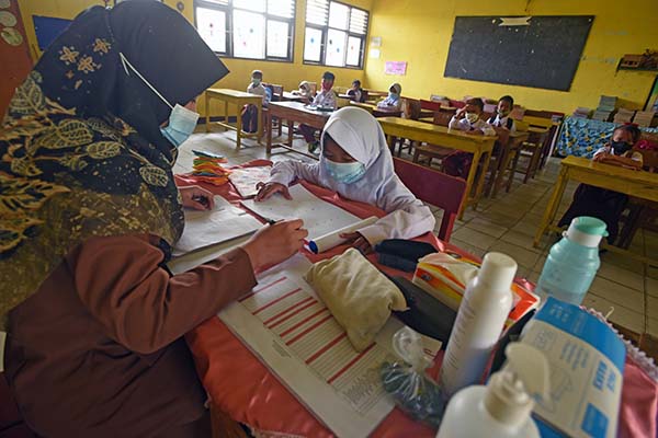 Guru membimbing siswa saat mengikuti proses belajar mengajar tatap muka terbatas di SD Negeri Pejaten I di Kramatwatu, Serang, Banten, Senin (23/8/2021). Pemerintah setempat secara selektif memberi izin bagi sekolah-sekolah di zona hijau memberlakukan pembelajaran tatap muka dengan pembatasan separuh dari kapasitas kelas serta penerapan protokol kesehatan. ANTARA FOTO/Asep Fathulrahman/wsj.