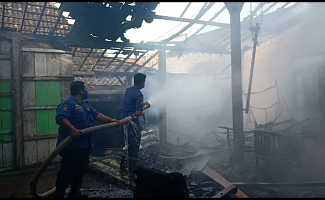 Petugas Damkar Satpol PP Grobogan sedang memadamkan api yang membakar sebagian rumah milik Munasih, di Desa Ngeluk, Kecamatan Penawangan, Senin (13/9/2021). (Solopos.com-Damkar Satpol PP Grobogan)