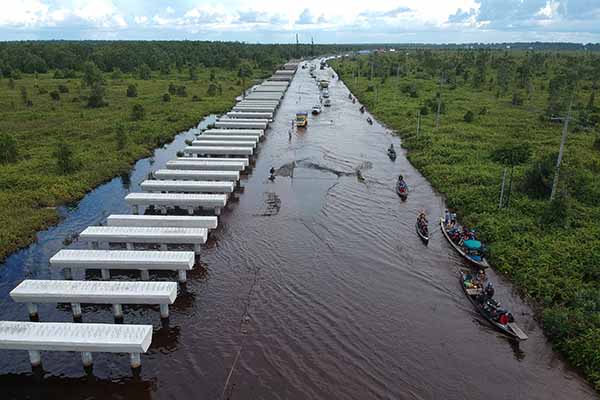 Foto udara pengendara motor menggunakan perahu bermesin (klotok) untuk melintasi banjir yang merendam di jalan trans Kalimantan Bukit Rawi, Pulang Pisau, Kalimantan Tengah, Kamis (23/9/2021). (Antara/Makna Zaezar)