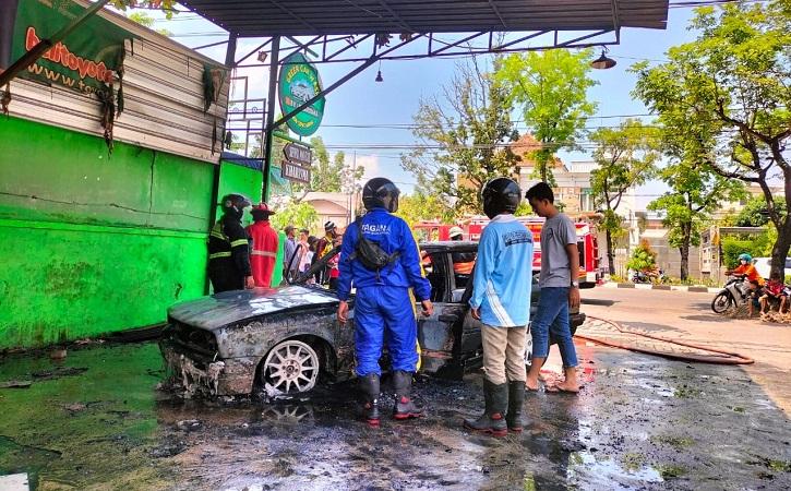 Petugas memeriksa kondisi mobil BMW yang terbakar di tempat pencucian mobil pada Kamis (16/9/2021) siang. (Istimewa/Dok Polsek Laweyan)
