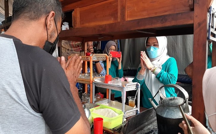 Bupati Sukoharjo Etik Suryani berdialog dengan pasangan suami istri Cahyo Yulianto, 50 dan Wiwin Haryati, 48 di lapak wedangan di depan SMP Negeri 3 Kartasura, Jumat (17/9/2021). (Solopos.com/Indah Septiyaning Wardani)