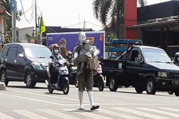 Mumun, nenek silver mengamen di jalanan di Tangerang Selatan sembari menggendong cucunya yang juga dilumuri cat silver, beberapa waktu lalu. (suara.com)
