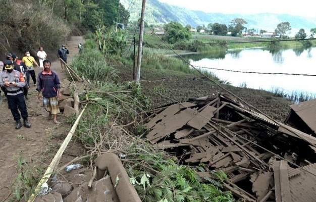 Warga dan petugas berjalan di dekat rumah yang rusak tertimbun longsoran bukit akibat gempa di kawasan Trunyan, Kintamani, Bangli, Bali, Sabtu (16/10/2021). (Antara)