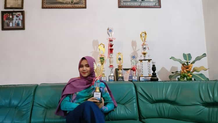 Mahasiswa Prodi Pendidikan Sejarah, Fiska Amanda Mulia, menunjukkan piala juara 2 dan juara favorit Poster Competition di gelaran Aection 3.0 IPB. (istimewa)