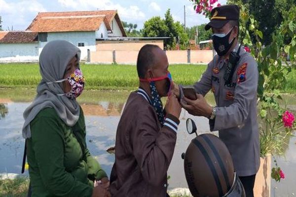 Polisi memberikan masker gratis ke pengendara yang melintas di Butuhan, Kecamatan Delanggu, Klaten, Kamis (21/10/2021). (Solopos.com/Ponco Suseno)