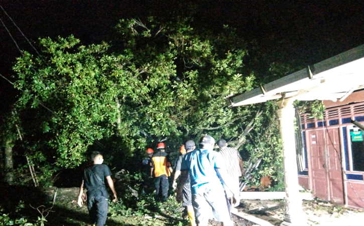 Para warga dan petugas BPBD Sragen meengevakuasi pohon tumbang yang menimpa teras rumah warga di Dukuh/Desa/Kecamatan Gesi, Sragen, Senin (18/10/2021) malam.(Istimewa/BPBD Sragen)