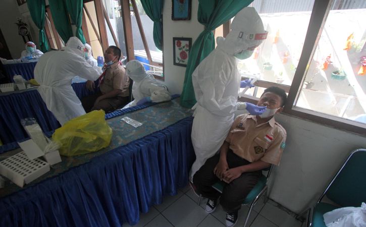 Petugas medis berbaju hazmat mengambil sampel lendir siswa saat tes usap PCR di SMP Negeri 8, Solo, Jumat (22/10/2021). (Solopos-Nicolous Irawan)