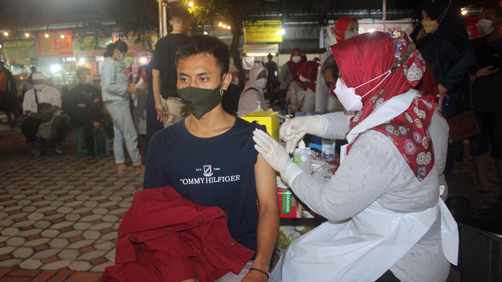 Seorang warga mengikuti kegiatan vaksinasi di sela-sela menikmati hidangan kuliner di sentra PKL Taman Kartini, Sragen, Sabtu (13/11/2021) malam. (Solopos.com/Tri Rahayu)