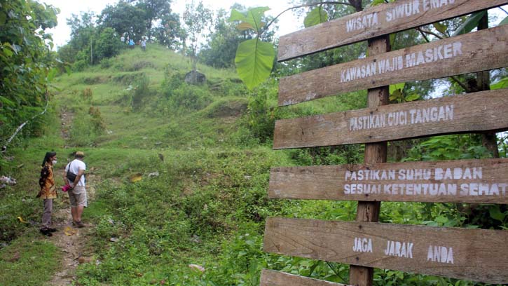 Sebuah papan penunjuk dan imbauan kepada pengunjung agar menjaga protokol kesehatan saat berwisata di Gunung Gandu yang terletak di wilayah Dukuh Duren, Desa Pilangsari, Gesi, Sragen, Minggu (28/11/2021). (Solopos.com/Tri Rahayu)