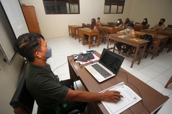 Guru SMP Negeri 13 Solo, Daryoto Handayu mengoperasikan laptop saat memberikan penjelasan kepada siswa saat Pembelajaran Tatap Muka (PTM) sekaligus Pembelajaran Jarak Jauh (PJJ) di sekolah, Rabu (24/11/2021). Di tengah kondisi pandemi Covid-19, guru didorong memanfaatkan tunjangan sertifikasinya untuk pengembangan penguasaan teknologi. (Solopos/ Nicolous Irawan)