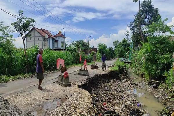 Warga melintas di jalan yang ambrol dan dipasangi kijing di Desa Ringinputih, Kecamatan Sampung, Kabupaten Ponorogo, Selasa (16/11/2021). (Abdul Jalil/Madiunpos.com)