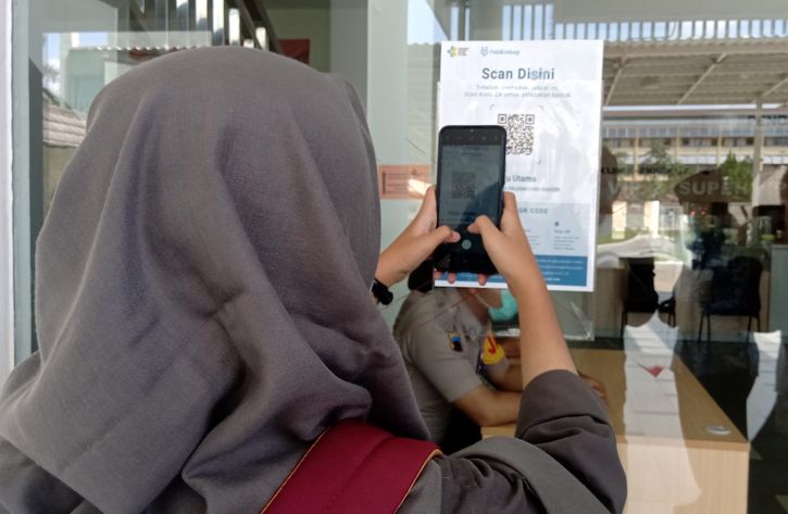 Seorang pengunjung memindai kode batang aplikasi PeduliLindungi dengan menggunakan ponselnya sebelum memasuki bangsal VIP RSUD dr. Soehadi Prijonegoro Sragen, Senin (29/11/2021). (Solopos.com/Tri Rahayu)
