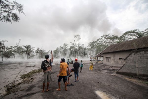 Warga melihat awan panas material erupsi Gunung Semeru yang mengalir di Sumber Wuluh, Lumajang, Jawa Timur, Minggu (5/12/2021). (Antara/Umarul Faruq)
