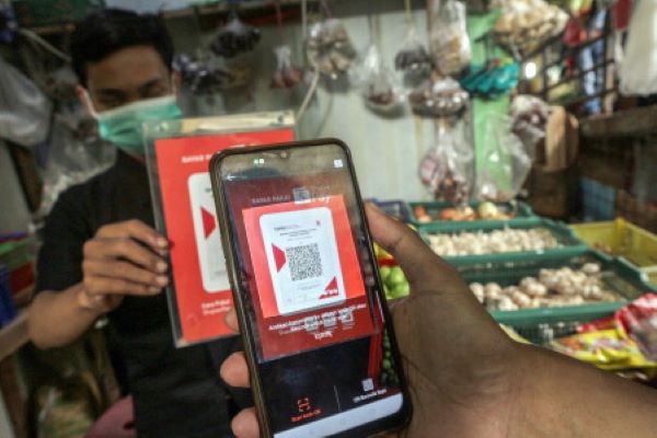 Warga bertransaksi digital menggunakan Quick Response Code Indonesian Standard (QRIS) saat berbelanja di Pasar Tradisional Cibinong, Kabupaten Bogor, Jawa Barat, Selasa (23/11/2021). (Antara/Yulius Satria Wijaya)