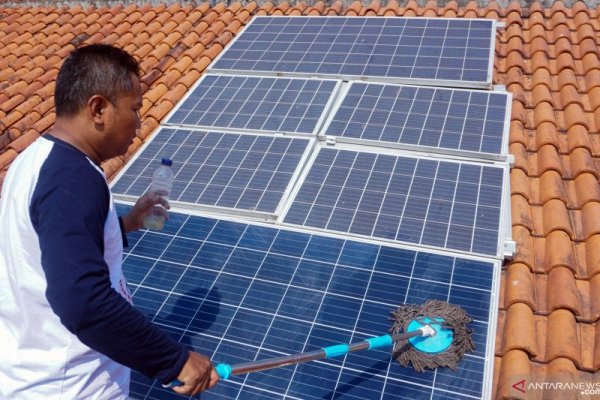 Seorang warga pemilik panel surya, Agus Nurokhim, membersihkan panel pembangkit listrik tenaga surya (PLTS) di atap rumahnya di Sragi, Kabupaten Pekalongan, Jawa Tengah, beberapa waktu lalu. (Antara/Harviyan Perdana Putra)