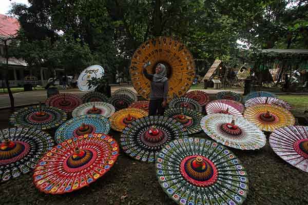 Pengunjung berfoto selfie dengan latar belakang hiasan payung yang terpasang saat acara Festival Payung 2021 di Taman Balekambang, Solo, Jumat (3/12/2021). (Solopos/Nicolous Irawan)