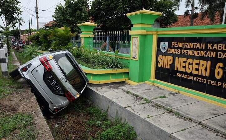 Kondisi mobil yang terperosok ke drainase di Jl. Dr. Sutomo, tepatnya barat SMPN 6 Sragen, Kelurahan Sine, Kecamatan Sragen, Minggu (5/12/2021). (Solopos.com/Wahyu Prakoso)