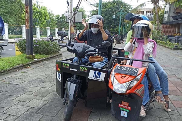 Tokoh difabel Solo yang juga pengajar di Yayasan Pembinaan Anak Cacat (YPAC) Kota Solo, Sugian Noor bersama anaknya mencoba motor modifikasi saat penyerahan di Omah Sinten Solo, Jumat (3/12/2021). (Solopos/Chrisna Chanis Cara)