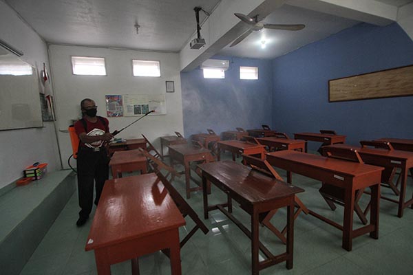 Petugas melakukan penyemprotkan cairan disinfektan di ruang kelas, SMA Warga, Solo, Kamis (27/1/2022). (Solopos/Nicolous Irawan)