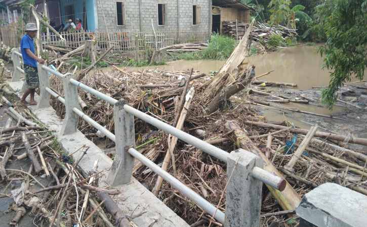 Warga menonton tumpukan sampah kayu yang menyumbat aliran air Kali Buntung di Jembatan Cendini, Kecamatan Bulu, Sukoharjo, Senin (17/1/2022). (Istimewa/Supri)
