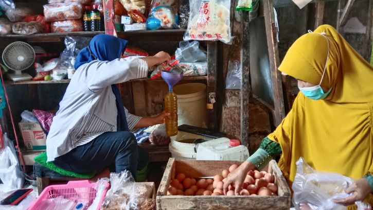 Seorang pedagang di Pasar Jungke, Karanganyar menakar minyak goreng curah untuk pembelinya, Jumat (21/1/2022). Hingga saat ini pedagang pasar tradisional masih menjual goreng dengan harga lama, yakni Rp19.000-Rp20.000 per kilogram. (Solopos.com/Akhmad Ludiyanto)