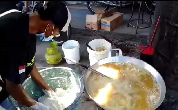 Seorang penjual gorengan sedang menggoreng jajanan di lapaknya di Kabupaten Madiun, Senin (25/1/2022). (Madiunpos.com/Abdul Jalil)