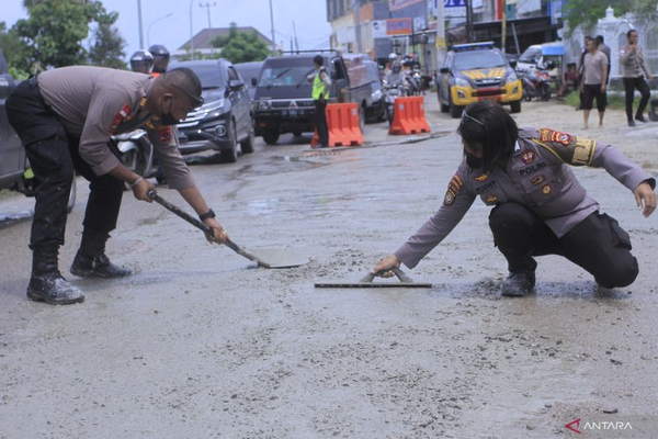Dua aparat kepolisian dari Polres Kupang Kota mengecor dan menambal sejumlah jalan berlubang untuk mencegah terjadinya kecelakaan lalu lintas akibat jalan berlubang di Kota Kupang, NTT, Jumat (28/1/2022).ANTARA FOTO/Kornelis Kaha.