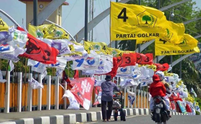 Pedagang mendorong gerobak berisi buah melintas di depan sejumlah bendera partai politik yang dipasang di jembatan Pantee Pirak, Kota Banda Aceh, Provinsi Nangroe Aceh Darussalam beberapa waktu lalu. (Antara/Ampelsa)
