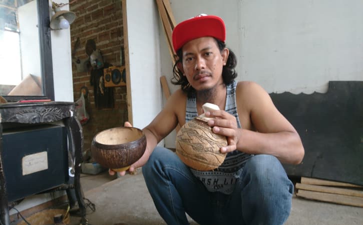 Pito Cahyono menunjukkan celengan dan mangkok yang terbuat dari limbah batok kelapa Jumat (27/5/2022). (Ronaa Nisa’us Sholikhah/Solopos.com)
