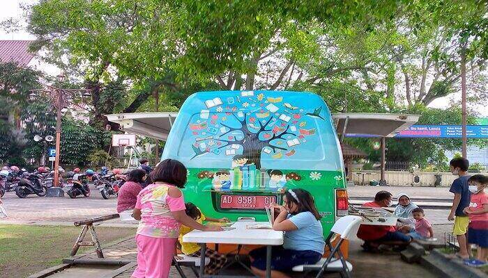 Anak-anak membaca buku dan mainan anak koleksi mobil perpustakaan keliling Dispersip Solo di Halaman Balai Kota Solo, Minggu (22/5/2022) (Solopos/Afifa Enggar Wulandari)