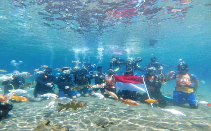 Para peselam mengibarkan bendera di dalam Umbul Ponggok, Desa Ponggok, Kecamatan Polanharjo setelah menggelar upacara bendera memeringati HUT ke-77 Kemerdekaan RI, Rabu (17/8/2022). (Istimewa/Pengelola Umbul Ponggok)