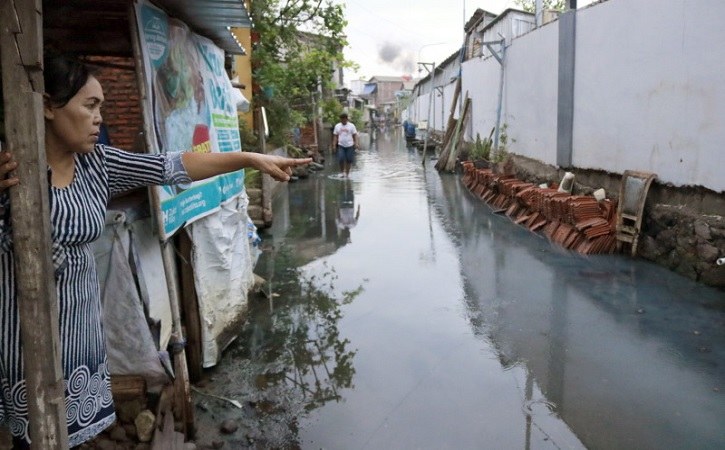 Warga Tambak Lorok, Semarang menunjuk ke jalan yang digenangi rob dan terancam tenggelam. (Bisnis/M Faisal Nur Ikhsan)
