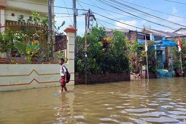 Seorang anak menerjang rob selepas dari sekolah di kawasan Kampung Tambaklorok, Kota Semarang, Senin (15/8/2022). (Solopos.com-Adhik Kurniawan)