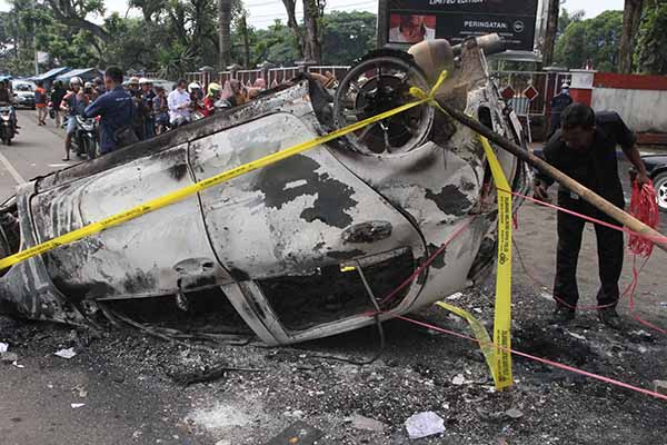Seorang warga melintas di samping mobil yang terbakar pasca kerusuhan di Stadion Kanjuruhan, Malang, Jawa Timur, Minggu (2/10/2022). Polda Jatim mencatat data sementara korban jiwa dalam kejadian tersebut berjumlah 127 orang dan 13 kendaraan rusak. ANTARA FOTO/Ari Bowo Sucipto/foc.