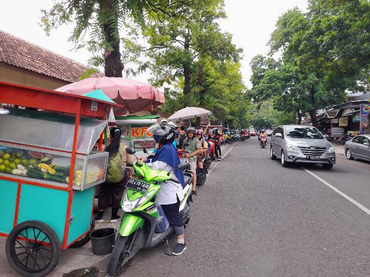 Para pengguna jalan berhenti untuk membeli dagangan para PKL di Jalan Setia Budi, samping SDN 4 Sragen, Jumat (18/11/2022). (Solopos.com/Tri Rahayu)